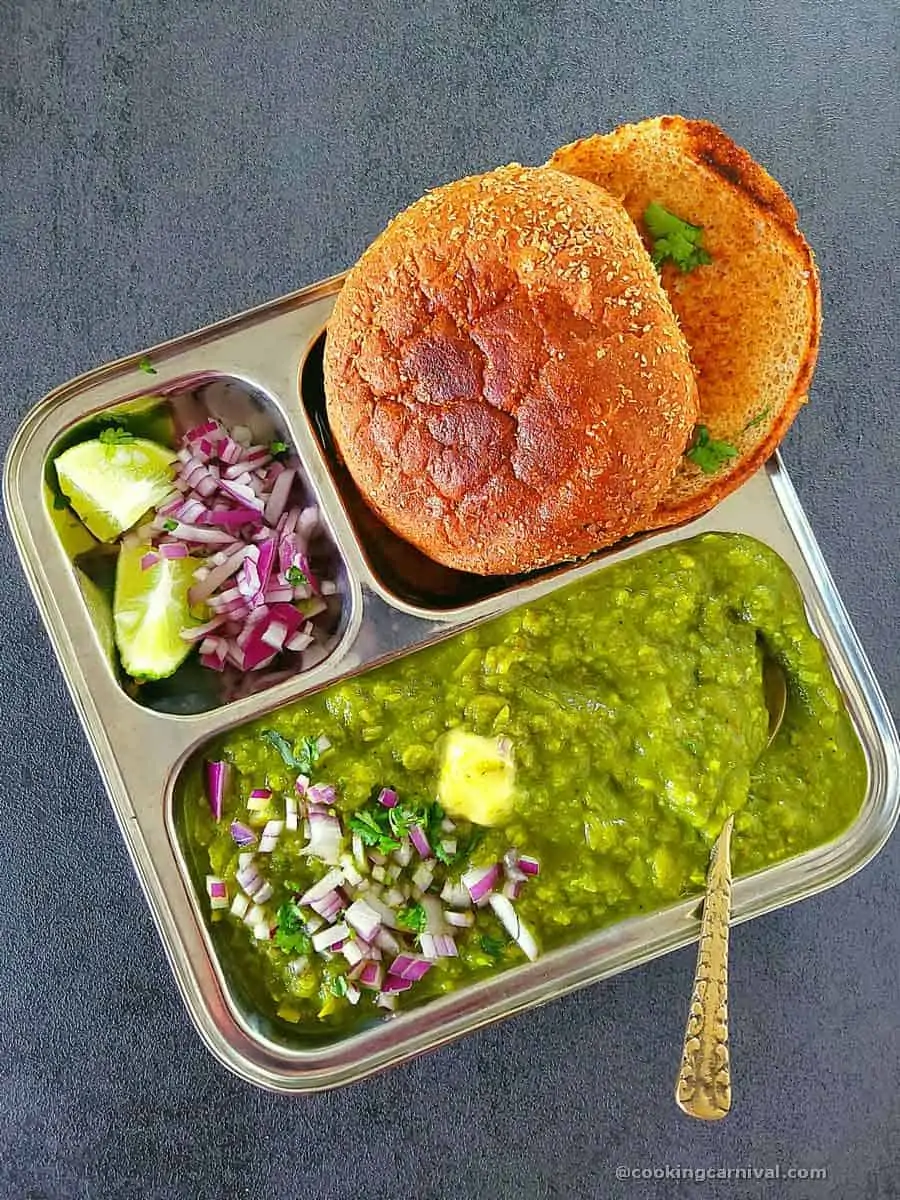 Bright green pav bhaji made with spinach, peas, capsicum, and herbs, served hot with buttered pav, chopped onions, and a lemon wedge, garnished with fresh coriander, popular street food from Surat.”